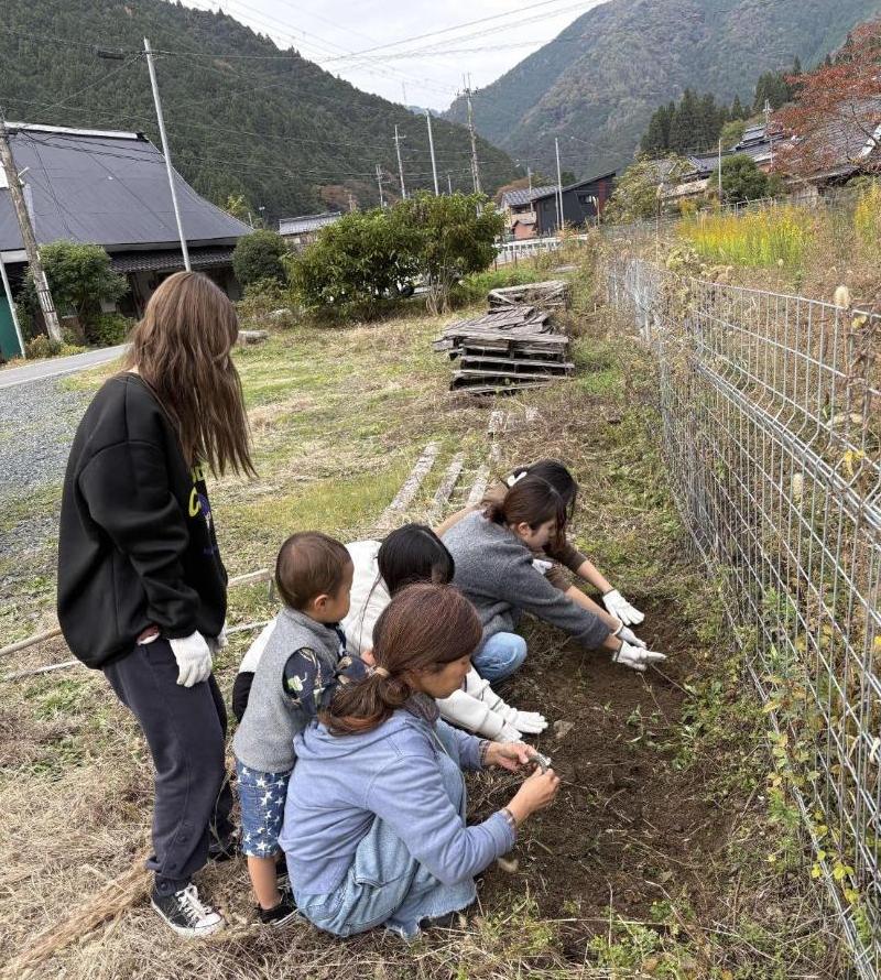 地域の方と、チューリップの球根を植えている学生たちの写真