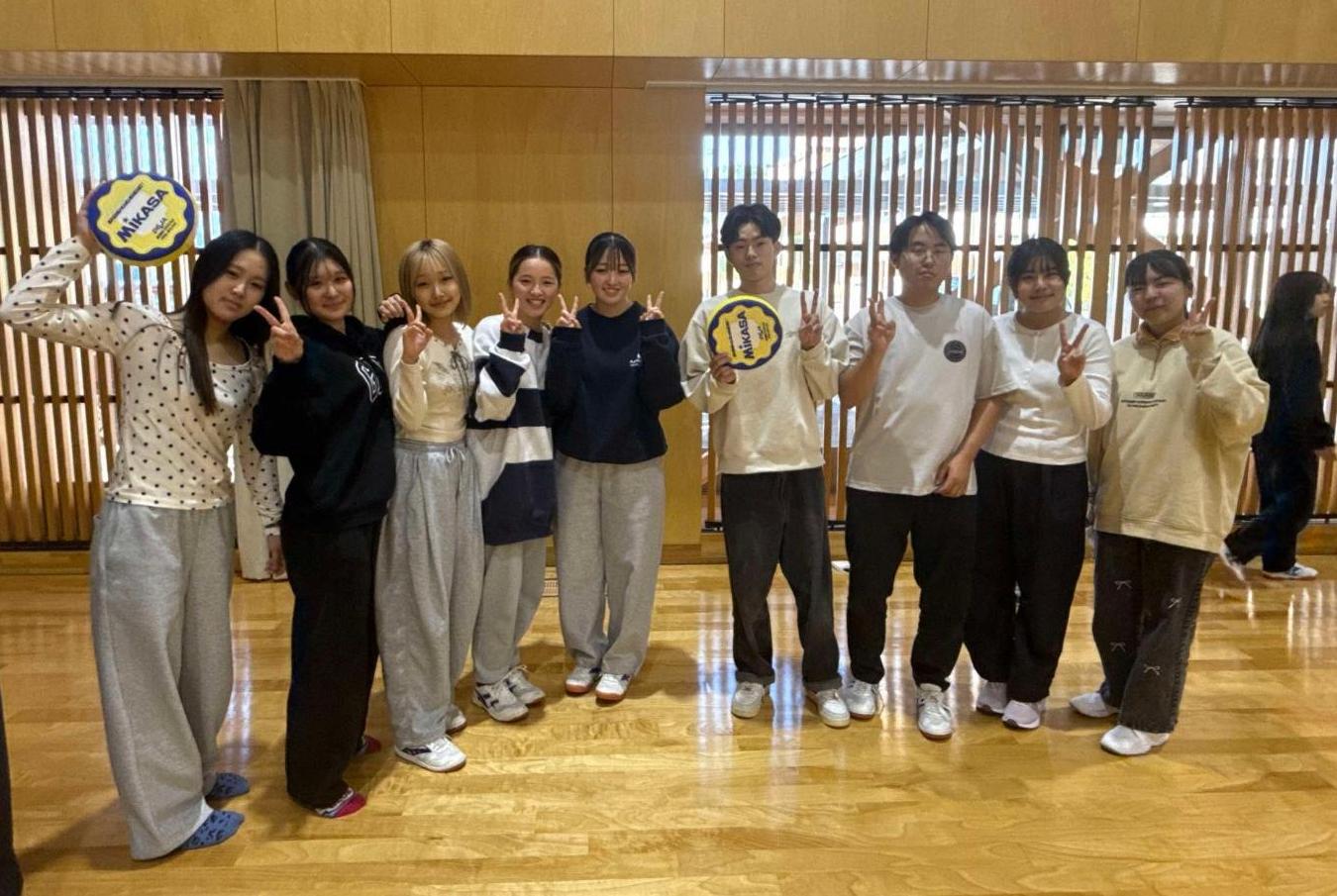 体育館でドッチビーの試合後にピースしている学生たちの写真
