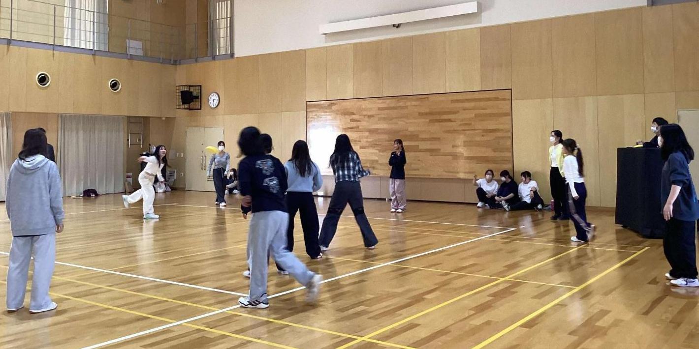 ドッチビー専用のフリスビーを投げた学生とそれを見て逃げようとしている学生たちの写真