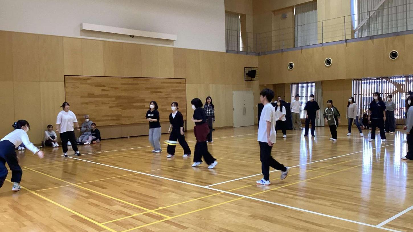 学生が投げた上フリスビーの方向を見ながら当たらないように移動しようとしている学生たちの写真