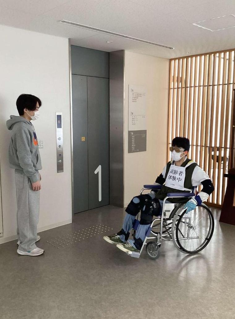 車椅子に乗ってゴーグルを付けた学生と付き添いの学生の写真