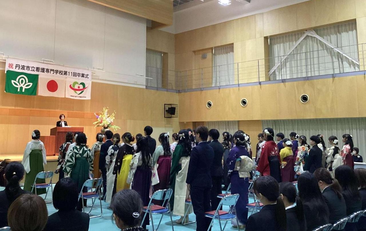 壇上の校長が整列した卒業生にお祝いの言葉を話しているところの写真