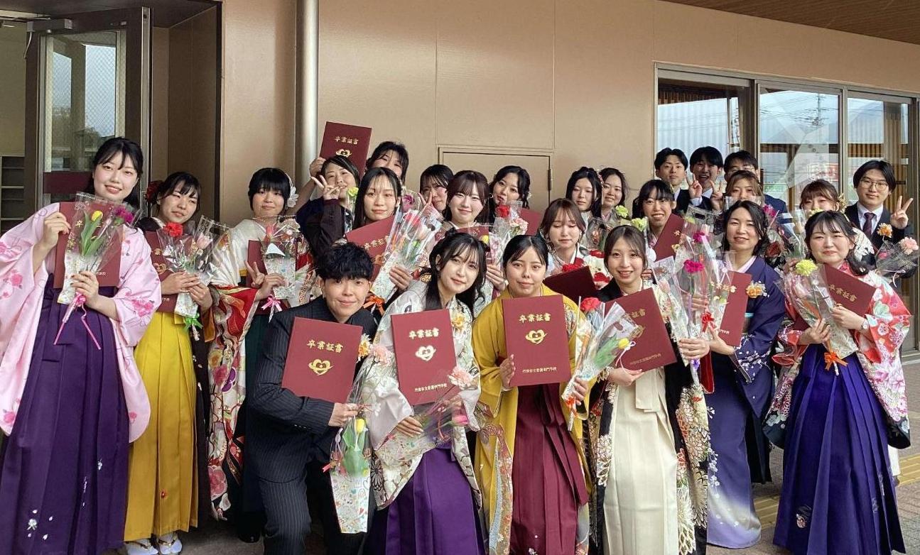 卒業式会場の外で、就職先から頂いたお花と卒業証書を持った卒業生達の写真