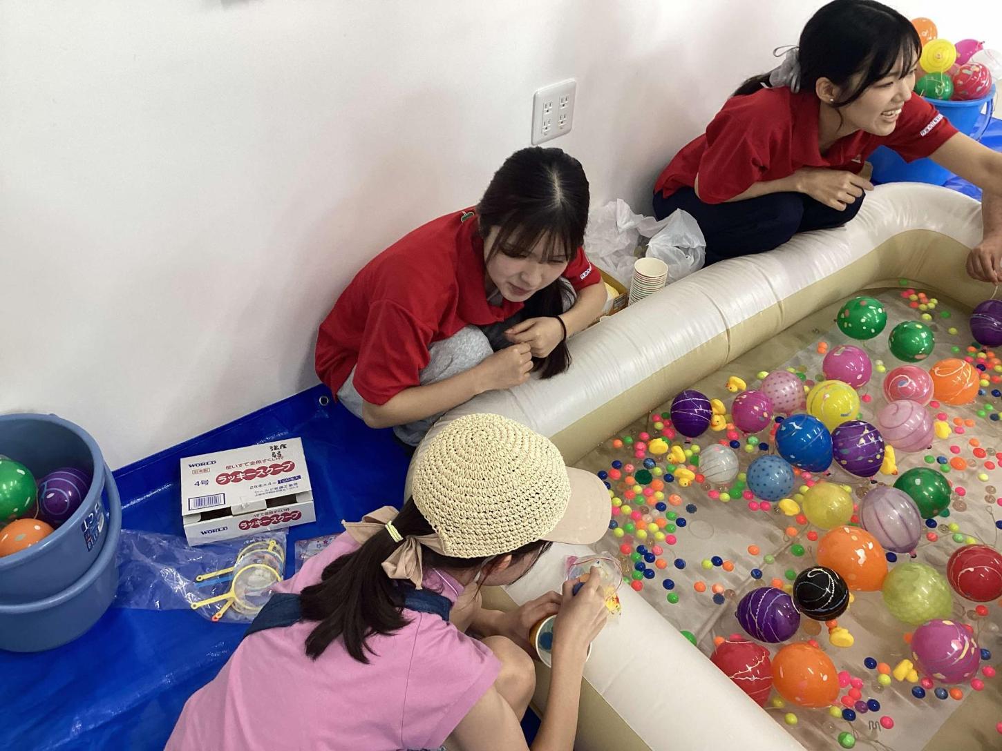 ボールすくいをしている参加者とその様子を見ている学生達の写真