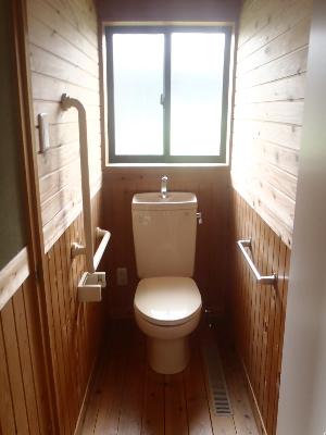 上に窓があり、木材の壁と床のトイレの写真