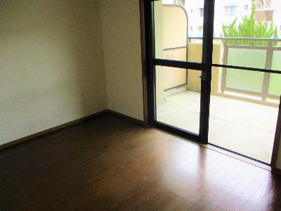 右に大きな窓があり、その先にベランダがあるフローリングの部屋