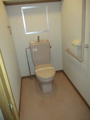 白を基調としたトイレで、床はベージュかかった色の写真