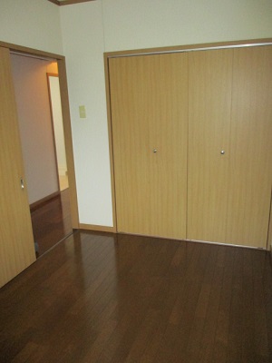 フローリングの部屋で、左側に廊下へ出る引き戸があり、正面には物入がある写真