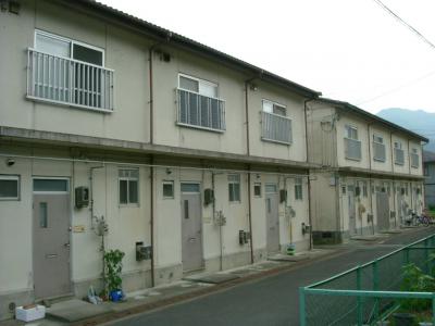 外壁がグレーで2階建ての団地の外観を斜めから撮影した写真