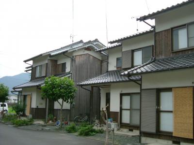 外壁の一部が木張りになっている、瓦葺屋根の2階建て団地の写真
