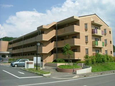 外壁がオレンジがかった茶色で3階建ての団地を斜めから撮影した写真