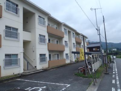 前に駐輪場がある外壁が白い3階建ての建物の写真