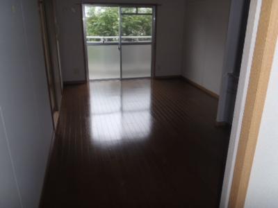 奥にある大きな窓から光が差し込んだフローリングの部屋の写真