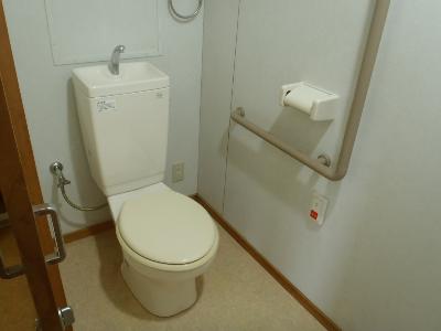 白を基調としたトイレで、床はベージュかかった色の写真