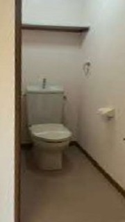 白を基調としたトイレで、床はベージュかかった色の写真
