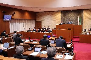 高校生と議員が議場で向かい合って席に座っている写真