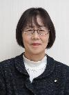 ネイビーの上着に白のハイネックを着て眼鏡をかけたボブカットの女性の写真