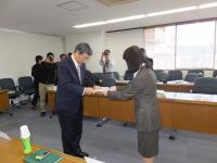 女性が男性に報告書を手渡している写真