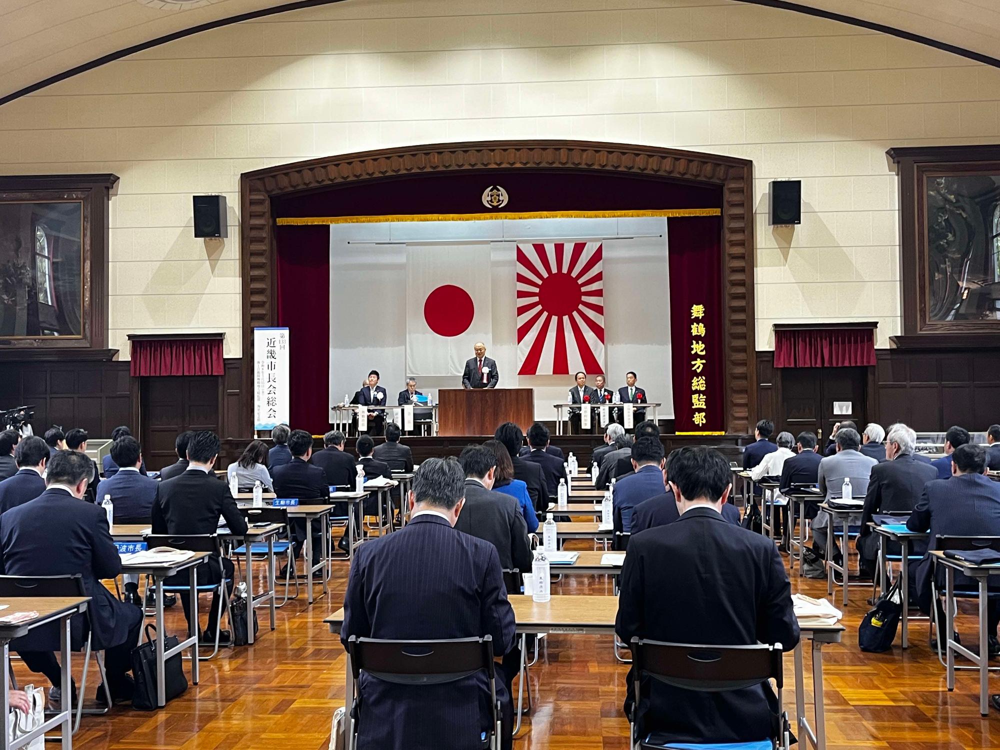 テーブル座り会議に参加するスーツ姿の男女の写真