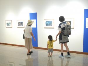 展示物を見ながら手を繋いで歩いている親子の写真