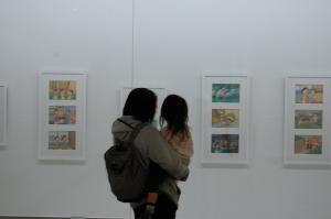 壁の展示物を眺めている親子の後ろ姿の写真