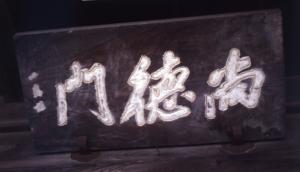 毛筆で尚徳門と白文字で書かれた木額の写真
