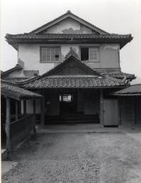 古い二階建ての家を正面から撮った白黒写真
