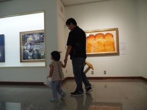 絵画が展示される美術館内を、手を繋いで歩く父親と娘の写真