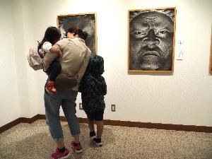 小さな女の子がお母さんに抱っこされて神様の写真を見ています。