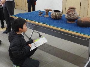 男の子が土器のスケッチをしています。