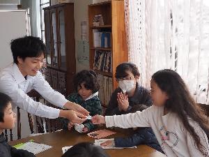 学芸員から記念のバッジを子どもたちにプレゼントしています。