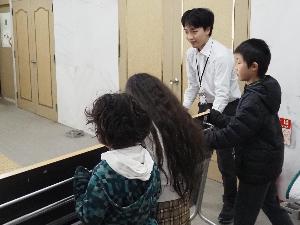 子どもたちと学芸員が一緒に作業机を運んでいます。