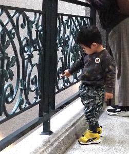 男の子が手すりの立体模様を指でなぞっています。