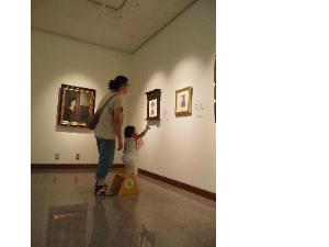 女の子が壁の作品を指さしながら見ています