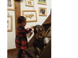 小さな女の子が犬の彫刻をやさしくなでています。