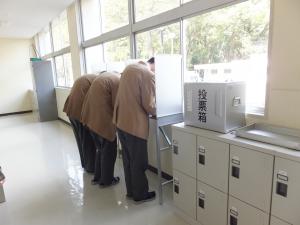 高校生三人が記載台で投票用紙を記入している写真