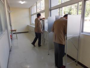 高校生が記載台で投票用紙を記入している写真